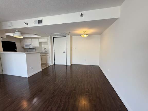 A room with a kitchen area and a doorway leading to another room.
