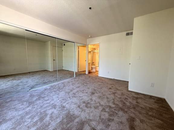 A room with carpeted floor and a doorway leading to another room.