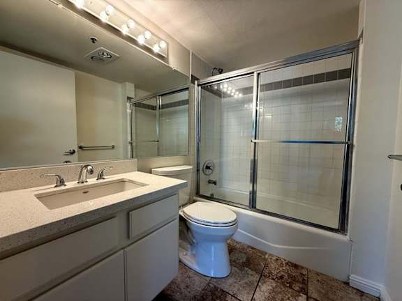 A white toilet sits in a bathroom with a walk-in shower.