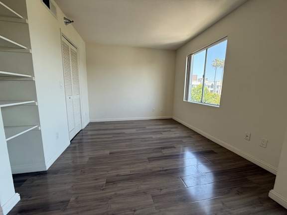 A room with wooden flooring and a window showing a view of a building outside.