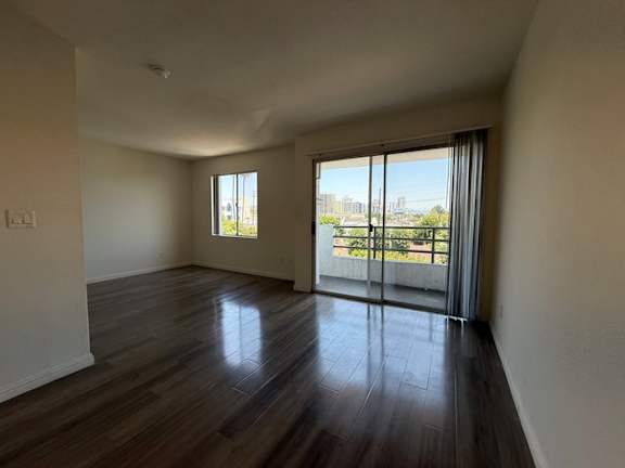 A room with wooden floors and sliding glass doors leading to a balcony.