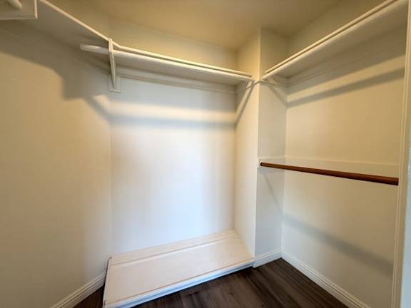 A white closet with a bench at the bottom.
