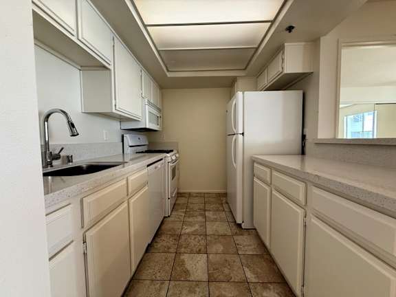 A kitchen with white cabinets and a white refrigerator.
