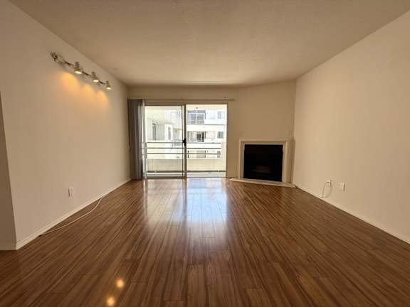 A room with wooden floors and a fireplace with a view of a city outside the window.