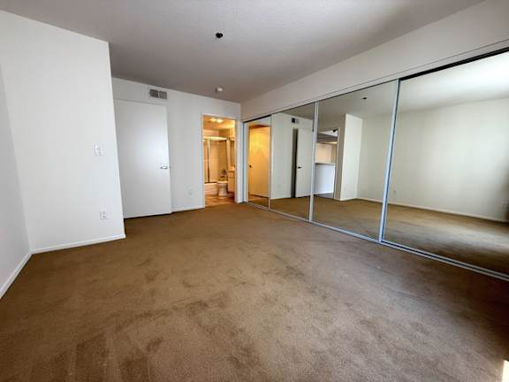 A room with a carpeted floor and a mirrored wall.