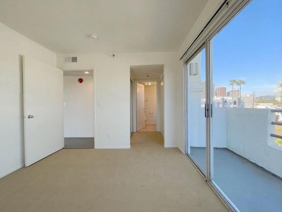 A room with a sliding glass door leading to a balcony.