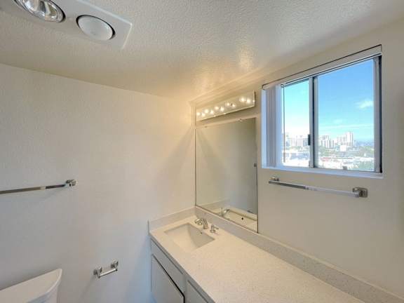 A bathroom with a white sink and a window overlooking a cityscape.