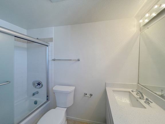A white toilet is in a bathroom with a sink and mirror.