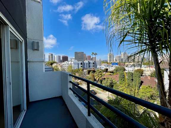 A balcony overlooks a cityscape with buildings and palm trees.