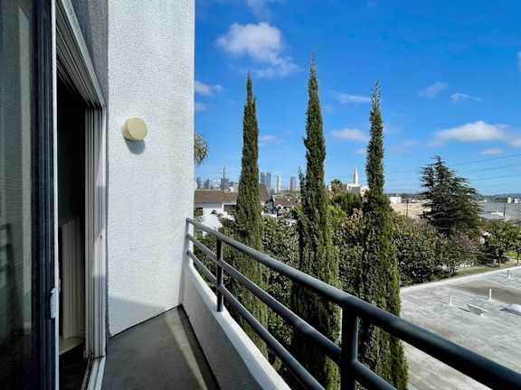 A balcony with a metal railing and a view of a city skyline.