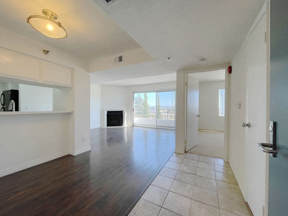 A spacious living room with a fireplace and a kitchen area in the background.