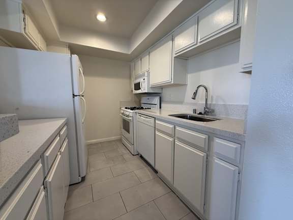 A kitchen with white appliances and cabinets.