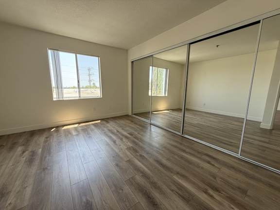 A room with wooden flooring and a large window.