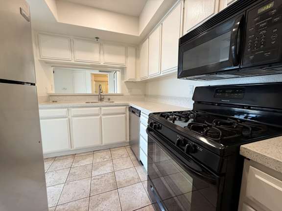 A kitchen with black appliances and white cabinets.