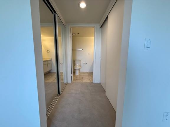 A hallway with a toilet visible through the door.