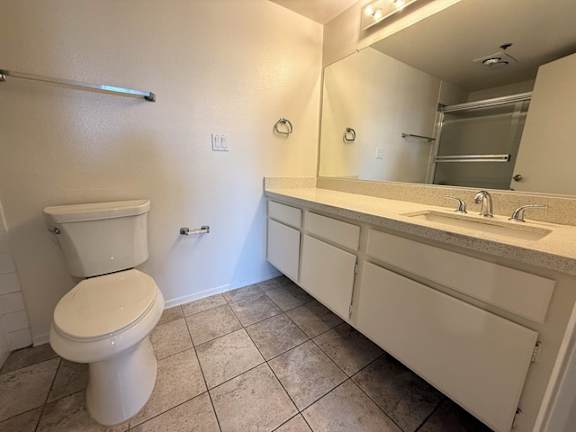 A white toilet sits in a bathroom next to a sink.