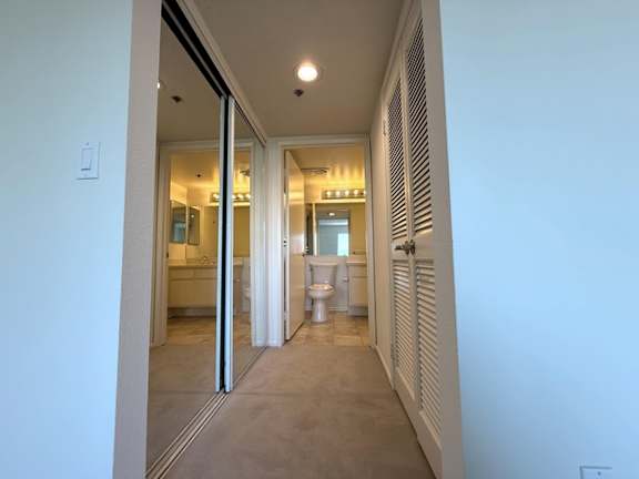 A bathroom with a toilet and sink is visible through a glass door.