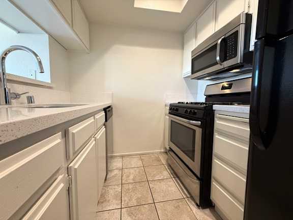 A kitchen with black appliances and white cabinets.