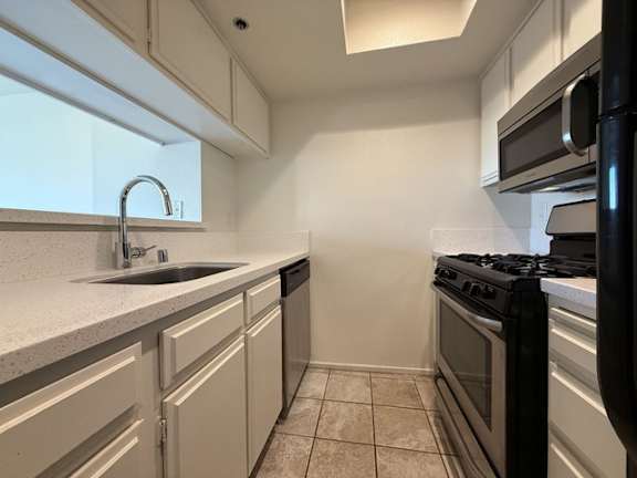A kitchen with a black stove top oven and white cabinets.