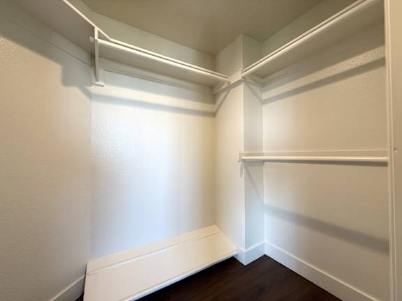 A white closet with a white bench at the bottom.