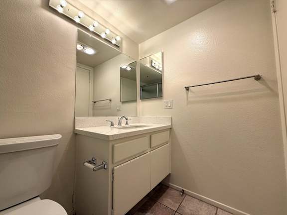 A bathroom with a white sink and a mirror with lights above it.