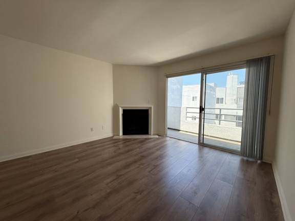 A large empty room with a fireplace and sliding glass doors.
