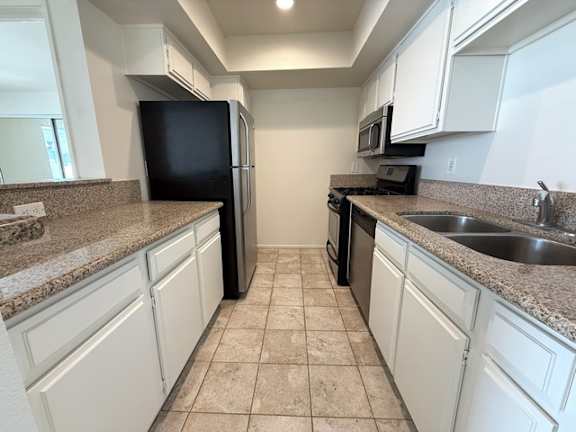 A kitchen with white cabinets and a black refrigerator.