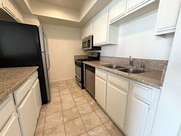 A kitchen with white cabinets and a black refrigerator.