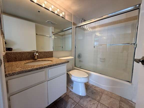 A white toilet sits in a bathroom with a sink and mirror.
