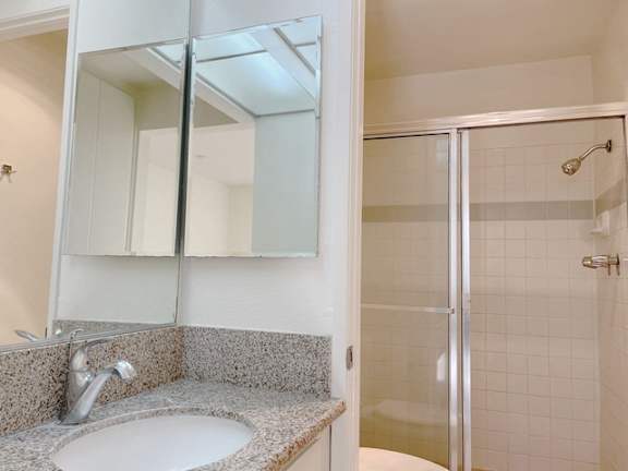 A bathroom with a sink, mirror, and shower.