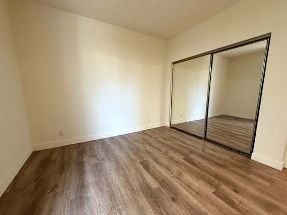 A room with wooden flooring and a large mirror.