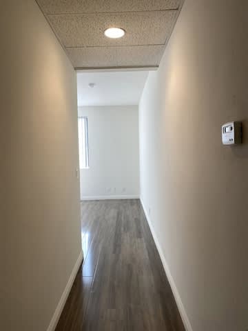 A long hallway with wood floors and white walls.