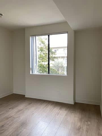 A room with a window and wooden flooring.