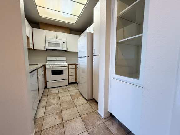 A kitchen with white appliances and cabinets.