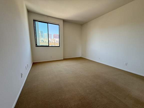 Empty room with a window overlooking a cityscape.