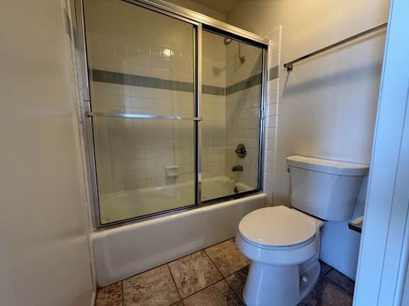 A white toilet sits in a bathroom next to a glass shower door.
