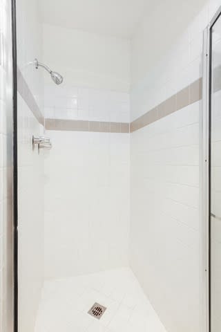A shower with a drain in the middle of the floor.