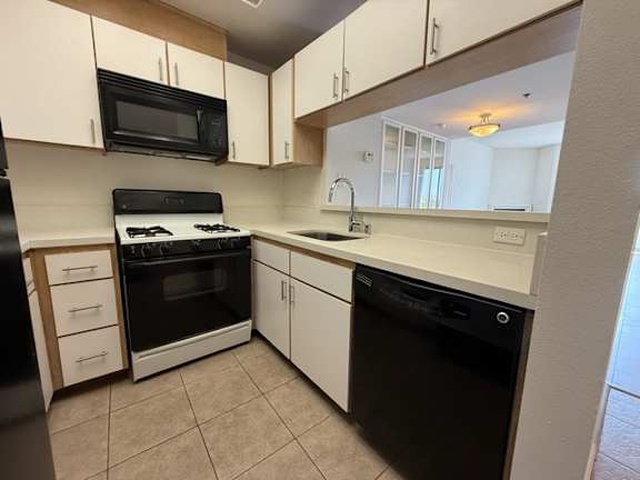 A kitchen with black and white appliances and white cabinets.