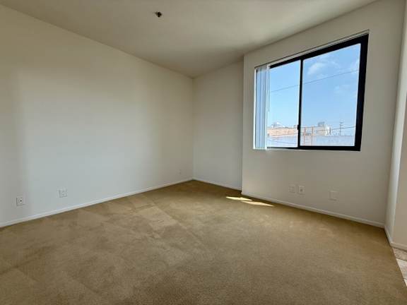Empty room with a window and carpeted floor.