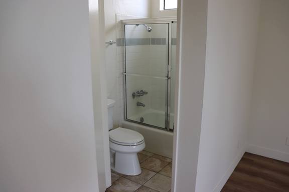A white toilet sits in a bathroom next to a walk-in shower.