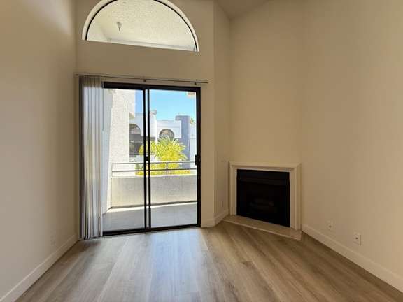 A room with a fireplace and a sliding glass door leading to a balcony.