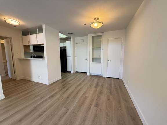 A kitchen area with a refrigerator, microwave, and cabinets.
