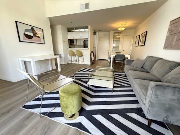 A living room with a grey couch and a striped rug.