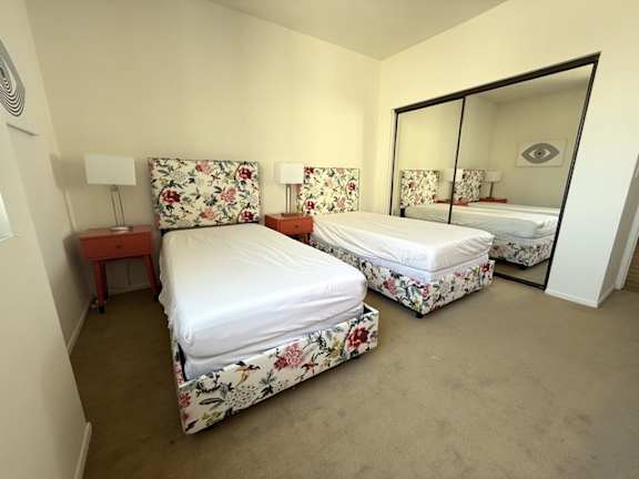 A bedroom with two beds and a mirror.