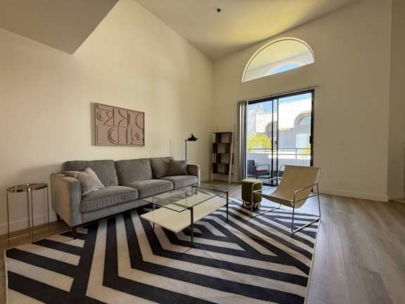 A living room with a grey couch and a striped rug.