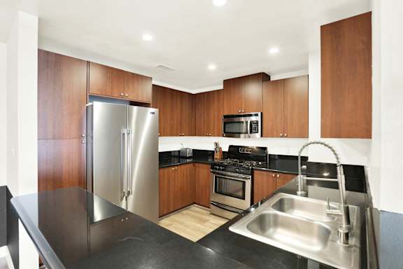 A modern kitchen with a stainless steel refrigerator, microwave, oven, and sink.