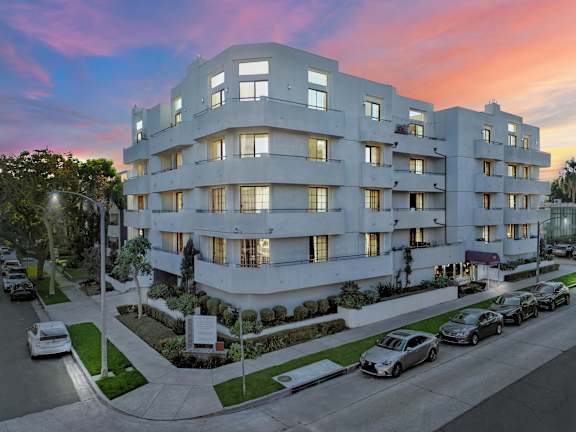 A modern apartment building with cars parked in front.