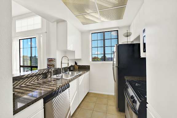 A modern kitchen with black granite countertops and white cabinets.