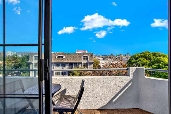 A balcony with a table and chairs overlooks a residential area.