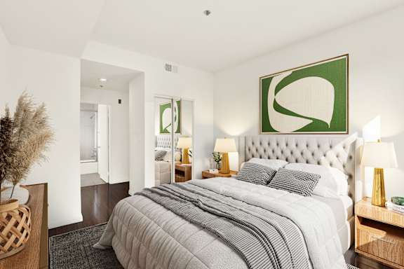A bedroom with a large bed and a green abstract painting above it.